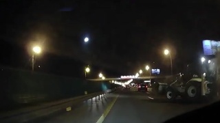 A tractor on the highway at night